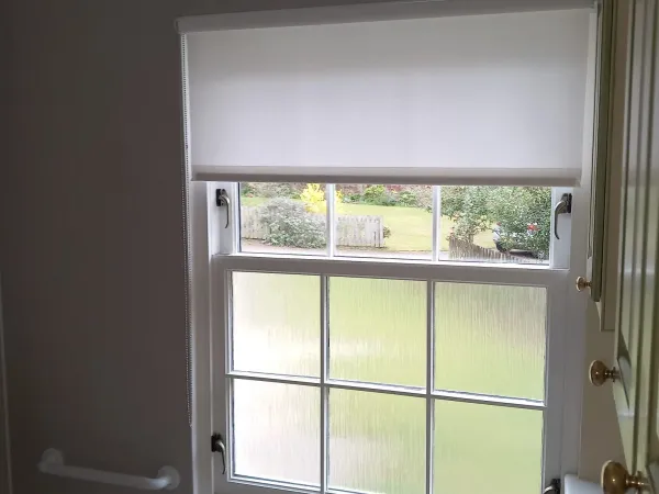 White moisture-resistant roller blind on a bathroom sash window