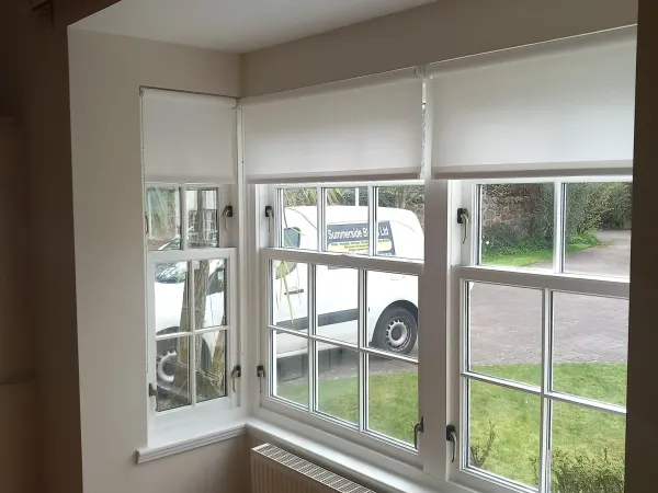 White roller blinds retracted on sash bay windows